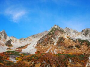 青空に映える宝剣岳の岩峰と紅葉の斜面