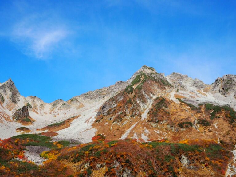 青空に映える宝剣岳の岩峰と紅葉の斜面